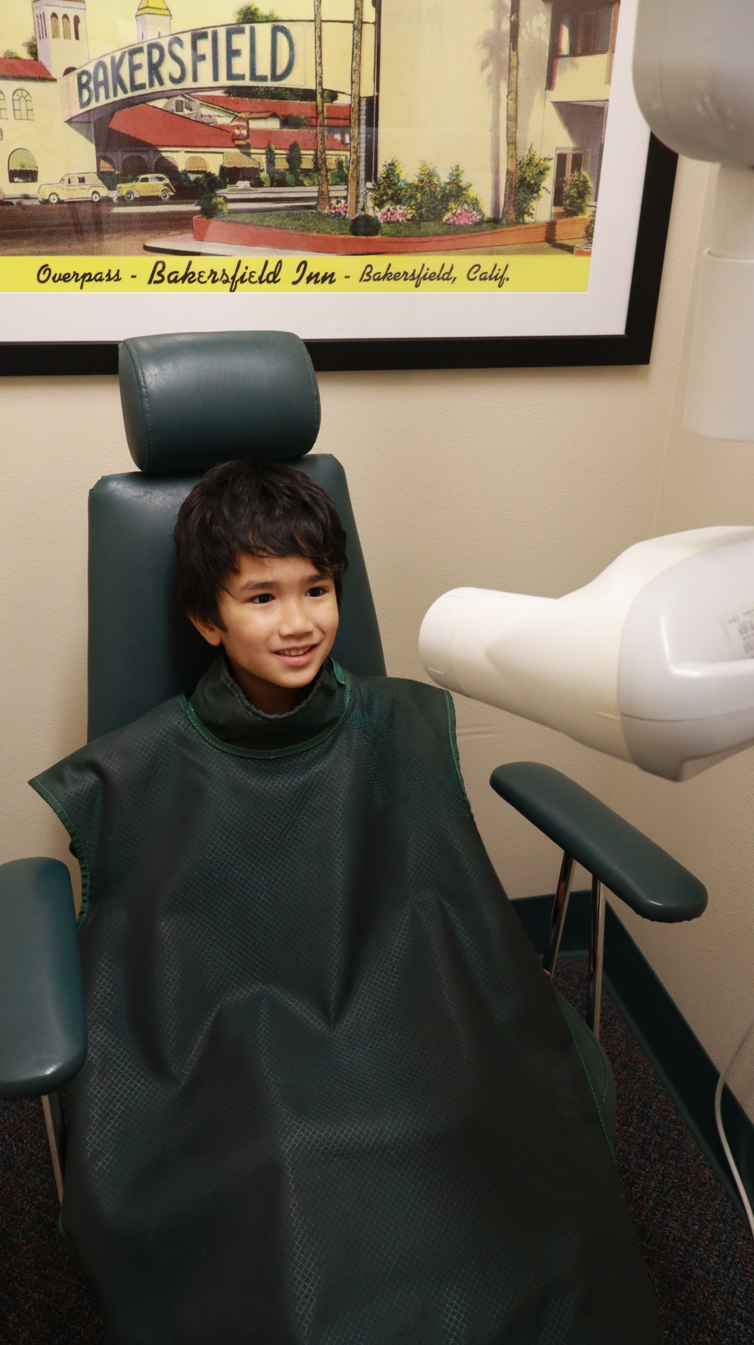 Smiling young patient wearing a lead apron before dental x-rays